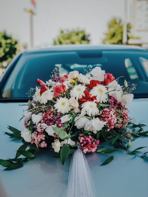 A large floral bouquet featuring an assortment of fresh flowers, including white daisies with yellow centers, pale pink roses, vibrant red and white lisianthus, clusters of small pink hydrangeas, and 